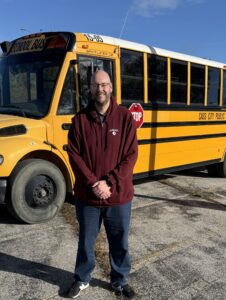 Eric Handby standing in front of a school bus