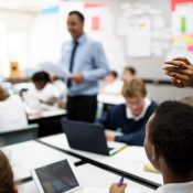 teacher in front of classroom and a student with their hand raised