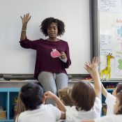 teacher with hand raised in front of her students